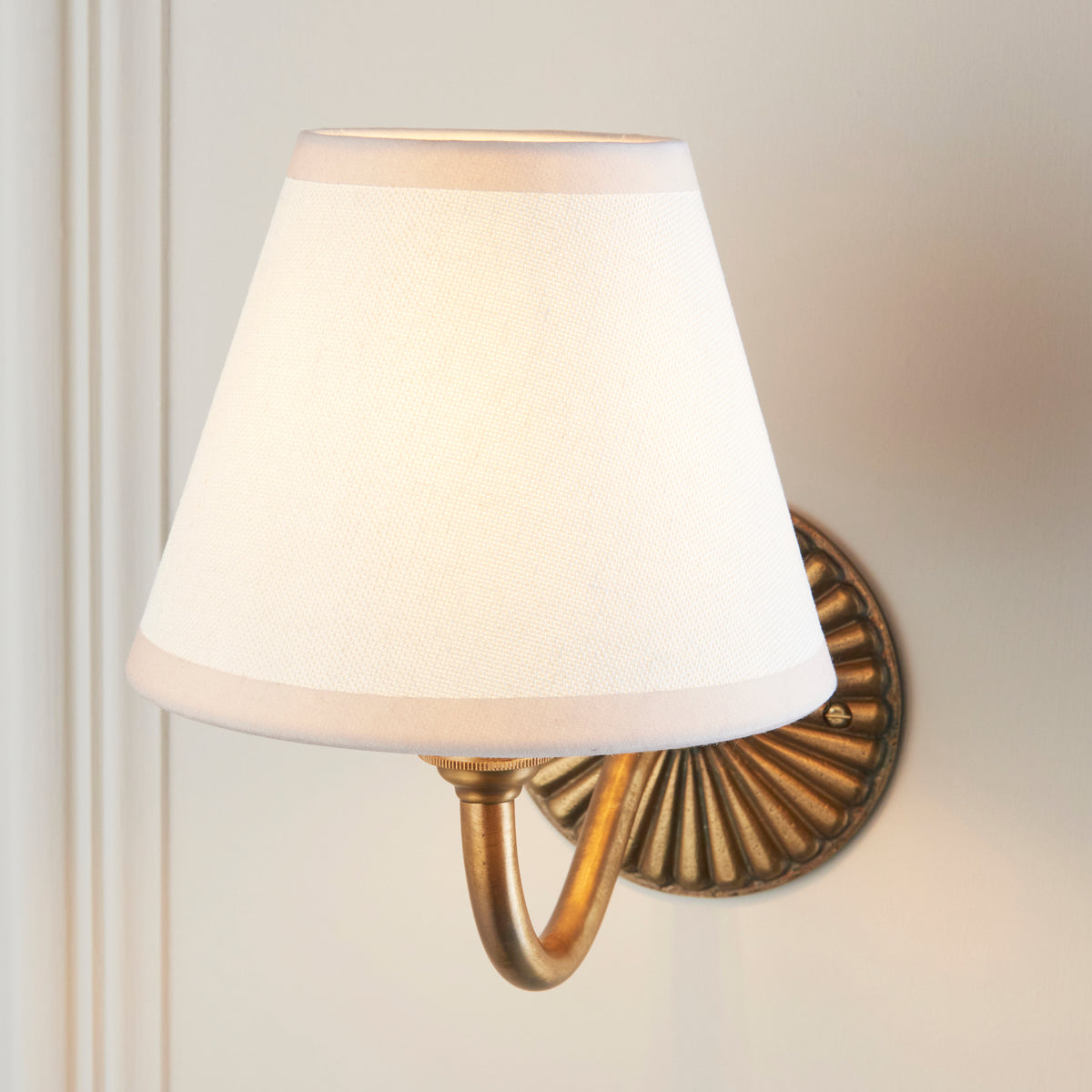 Close view of the cream fabric shade on the curved antique brass arm of the Dahlia Curve & Ivy light