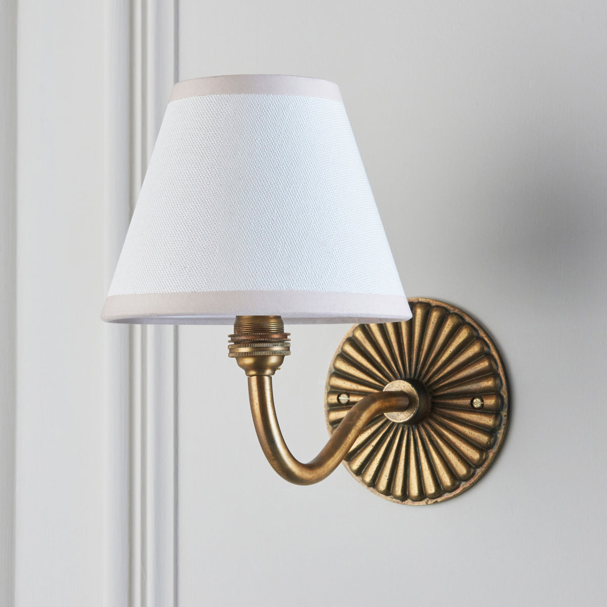 Side view of the Dahlia Curve & Ivy wall light, white fabric shade above a fluted brass backplate