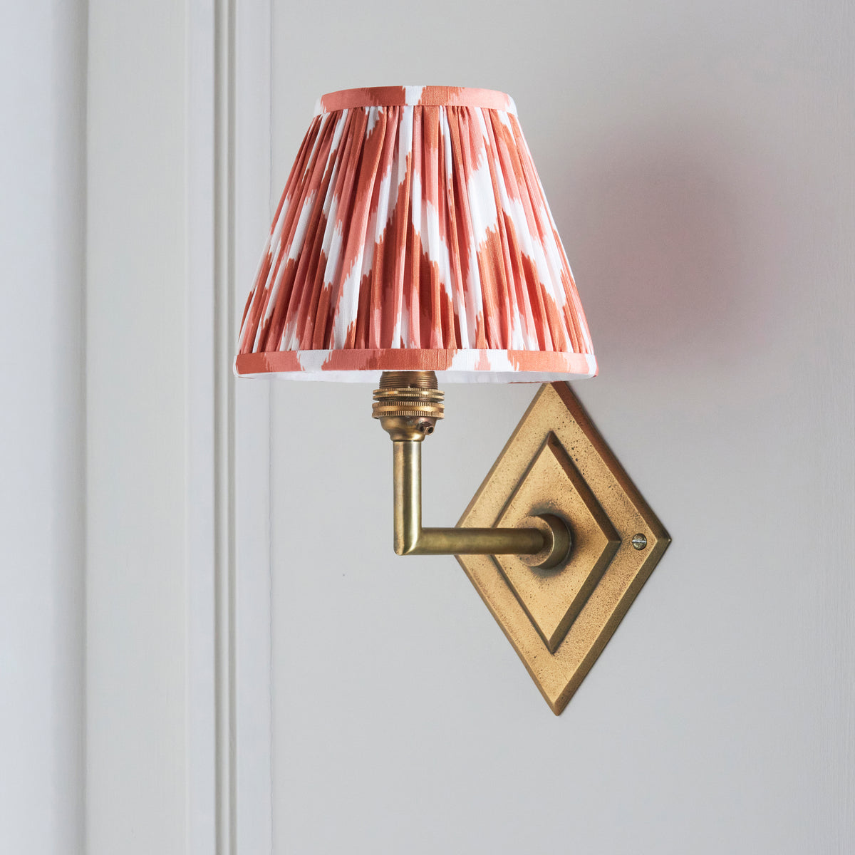 Side profile of the Diamond Angle brass wall light with pleated orange ikat shade