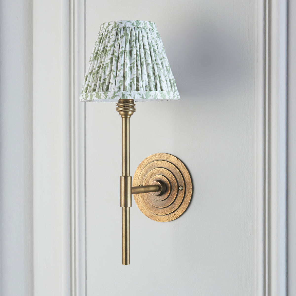 Side view of the Halo brass wall light with slim stem and green leaf pleated shade