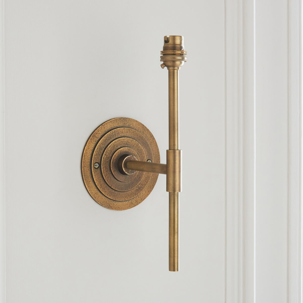 Halo Tall wall light without shade, showing antique brass stem, lamp holder and circular backplate