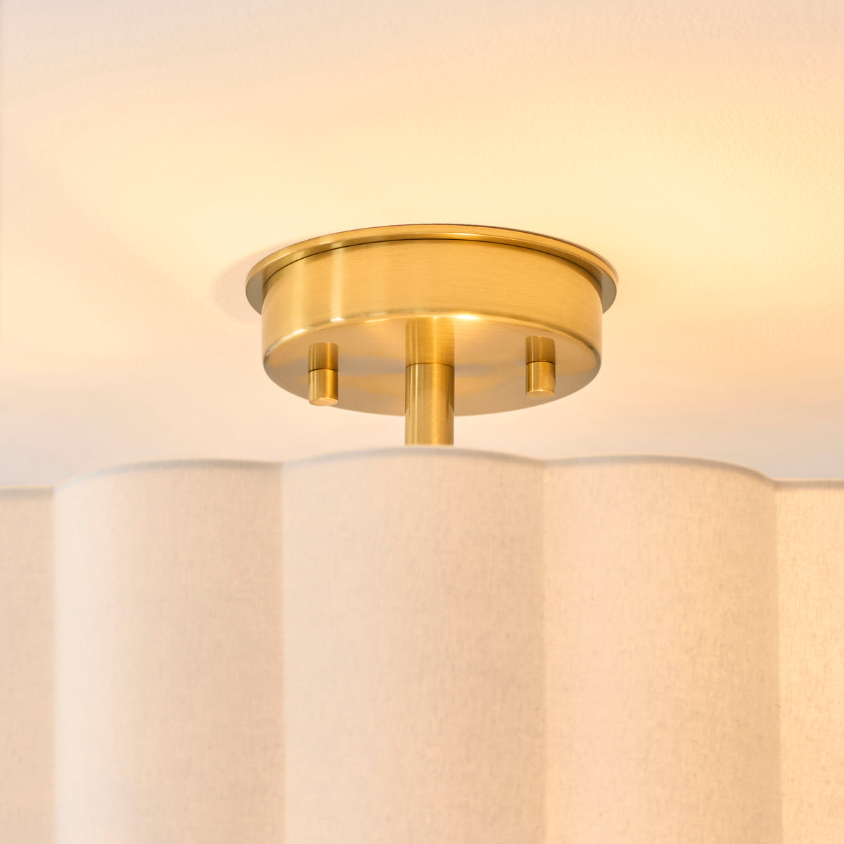 Close-up of the brushed aged brass ceiling plate and fixings above the scalloped fabric shade