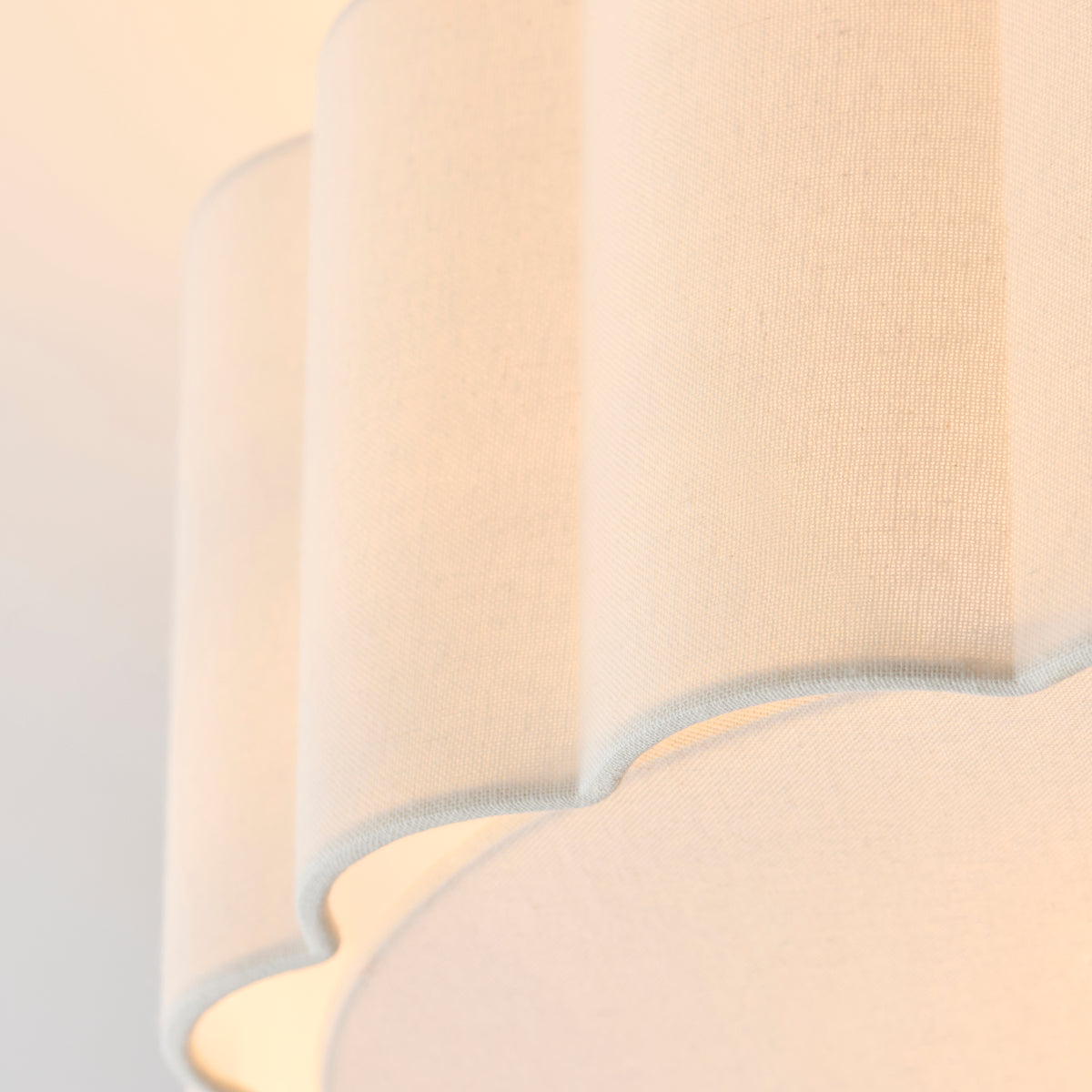 Close-up of the scalloped cream fabric shade edge, showing folds and stitched trim