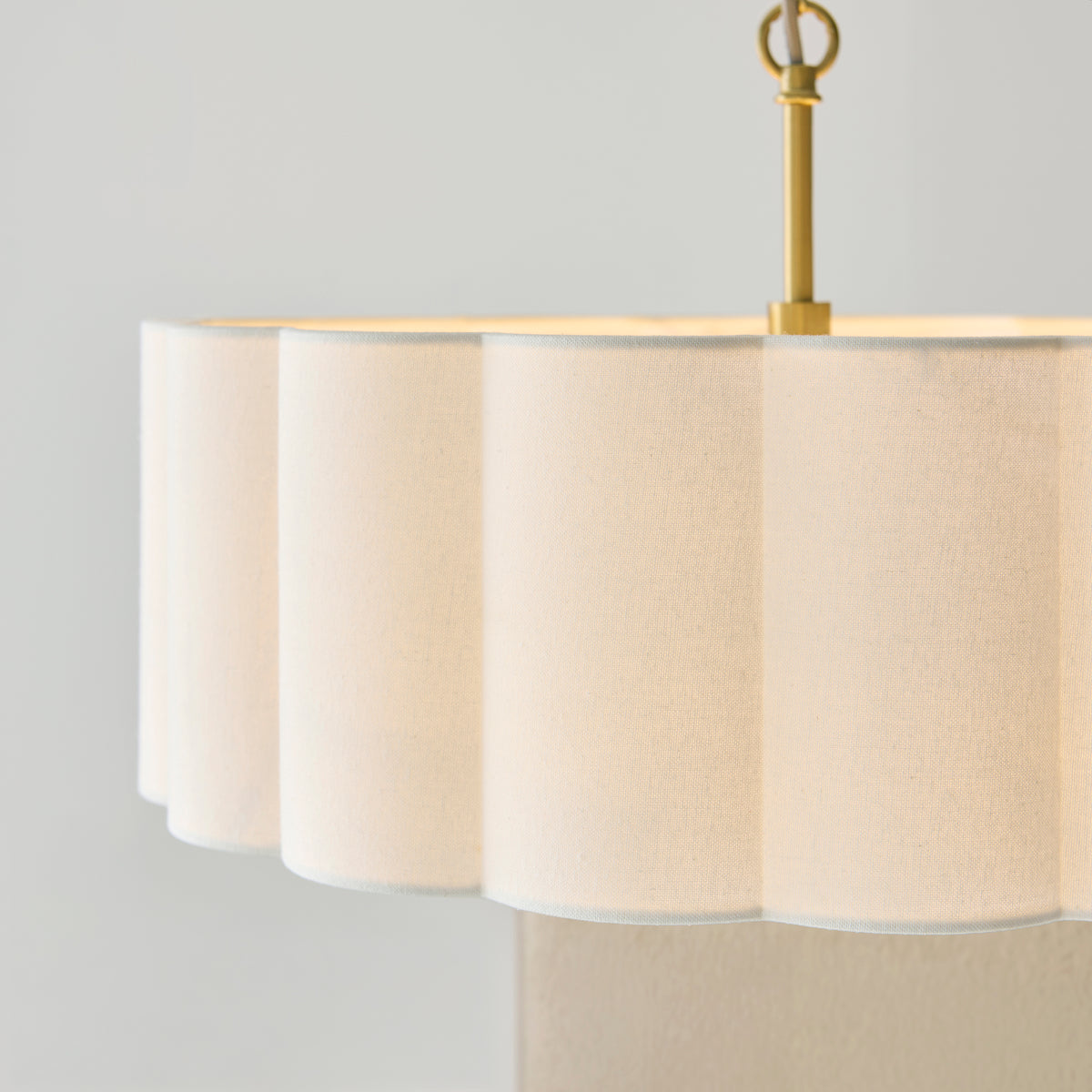Close-up of the fluted cream shade and brass suspension loop of the Serene pendant