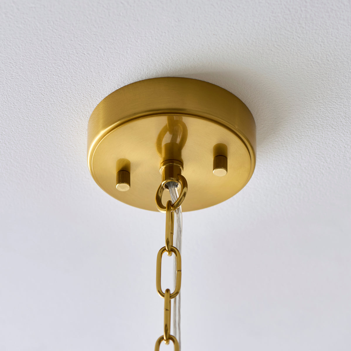 Close-up of clear ribbed glass rods suspended from brass rings on the Montpellier chandelier