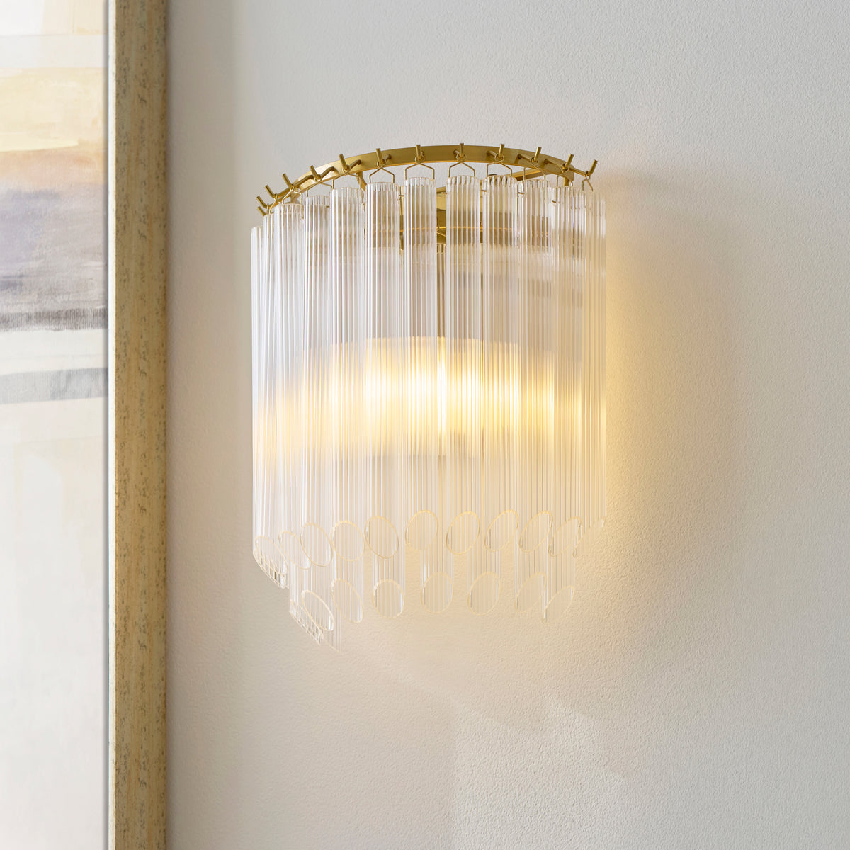 Lit Montpellier aged brass wall light casting warm light on a cream wall