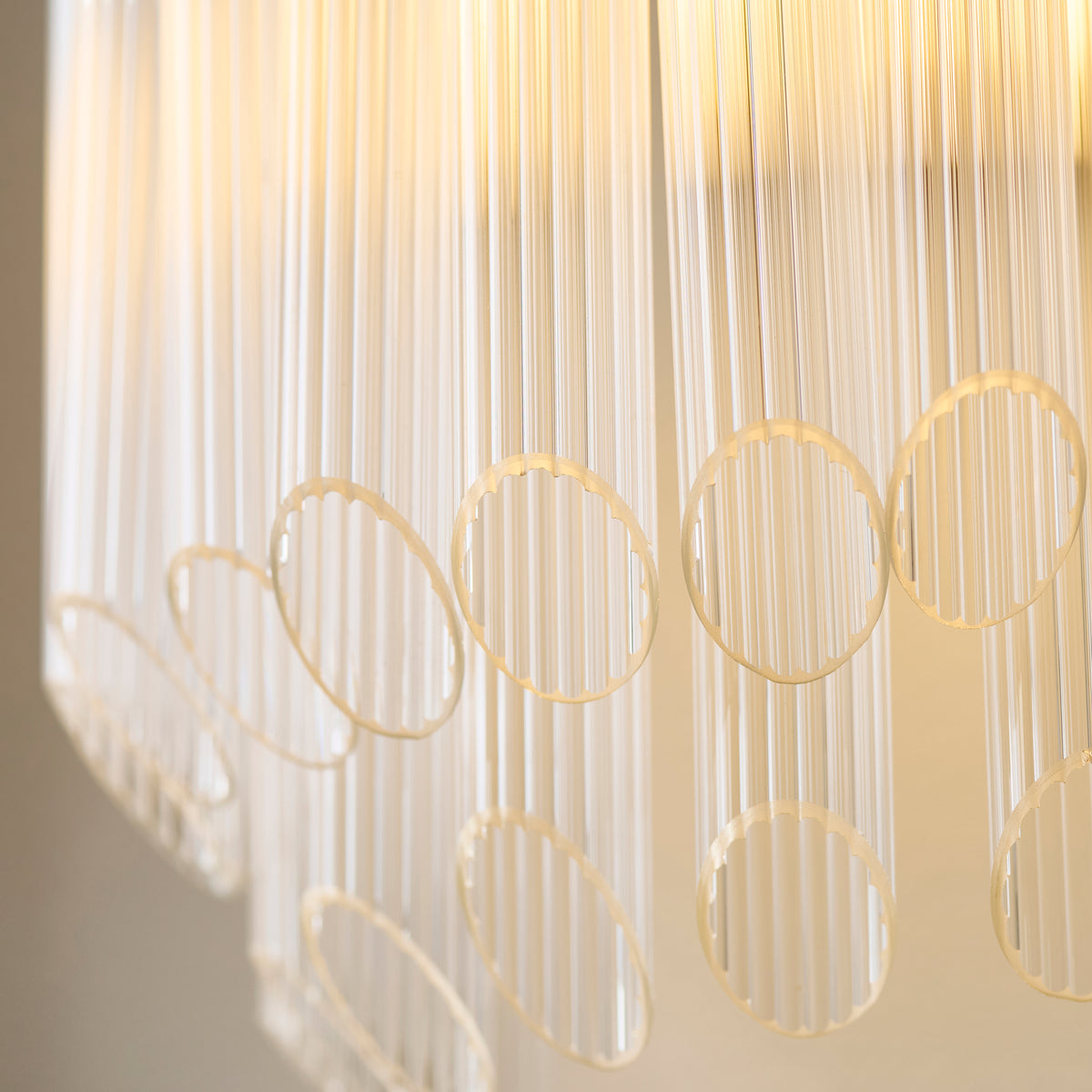 Close-up of glowing ribbed glass rods and brass loops on the Montpellier wall light