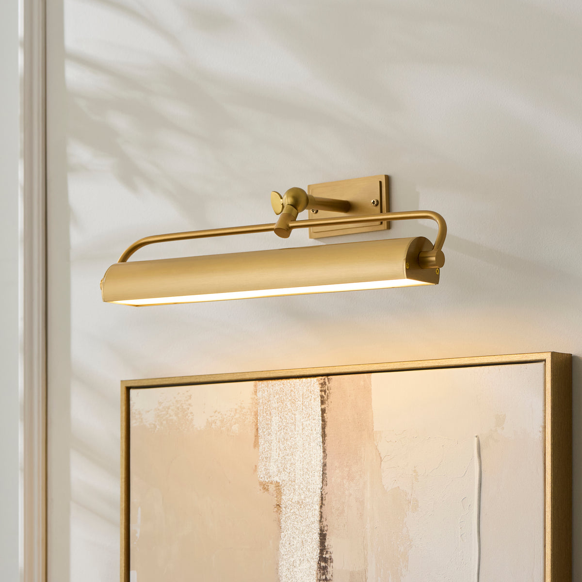 Lit Nantes brass picture light angled over the top of a framed textured artwork