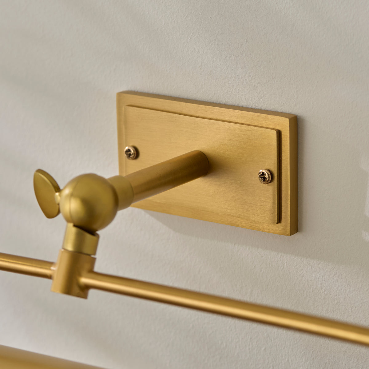 Close-up of the rectangular brass wall plate and adjustable knuckle joint of the Nantes light