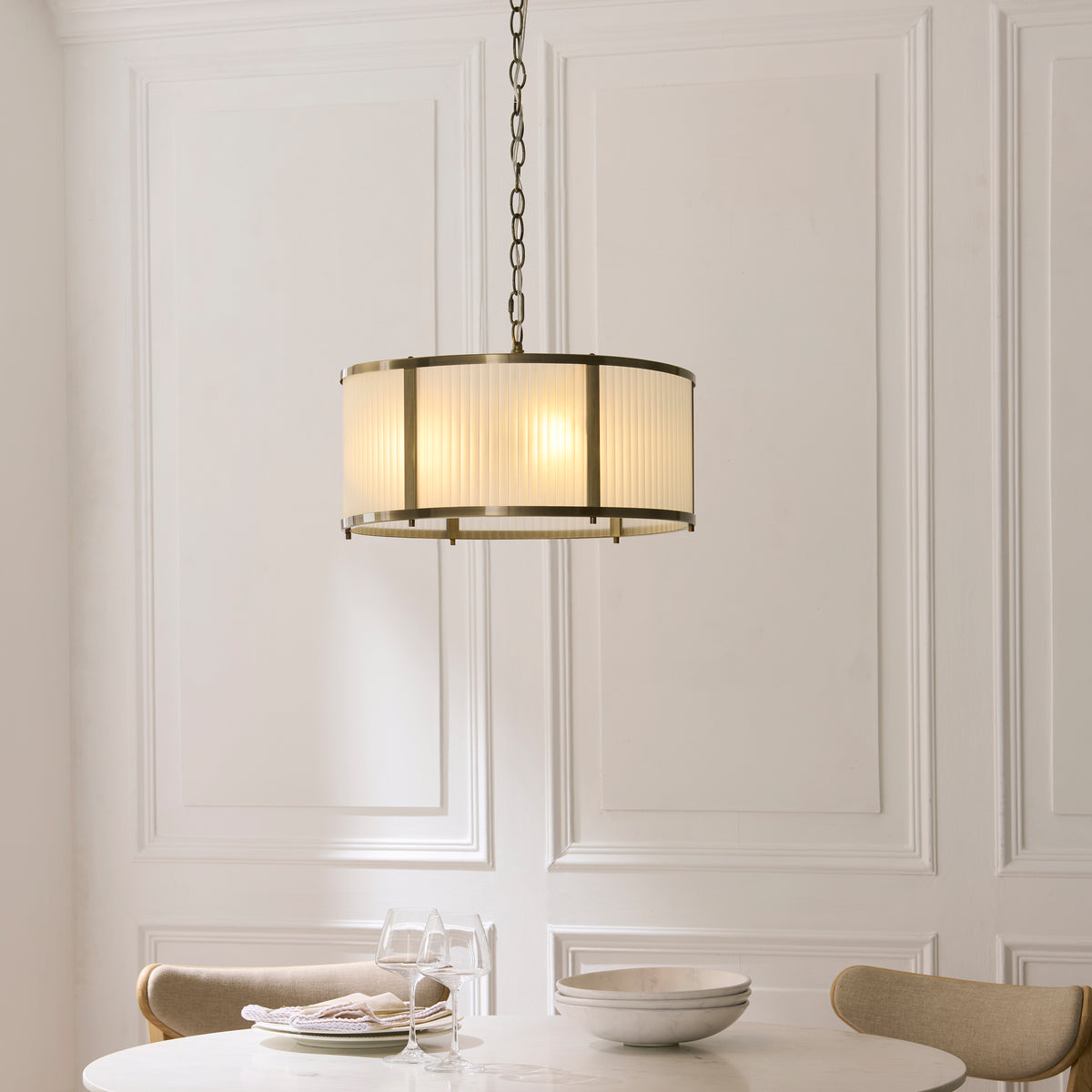 Ridgeton ribbed glass pendant lit above a round dining table with glasses and bowls