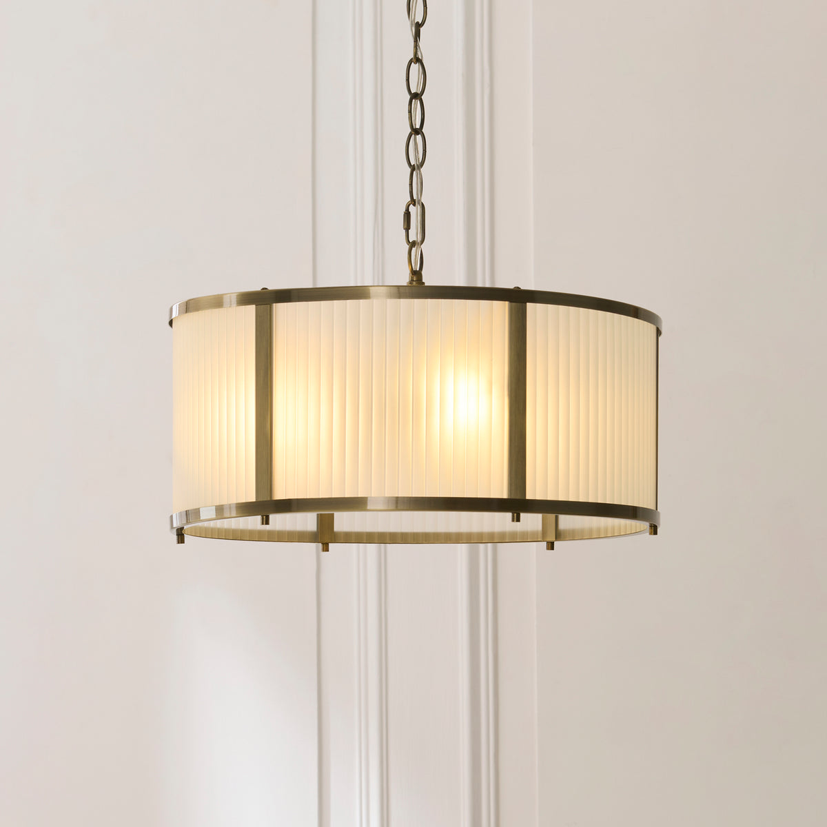 Lit Ridgeton pendant showing the ribbed glass drum shade in an antique brass frame
