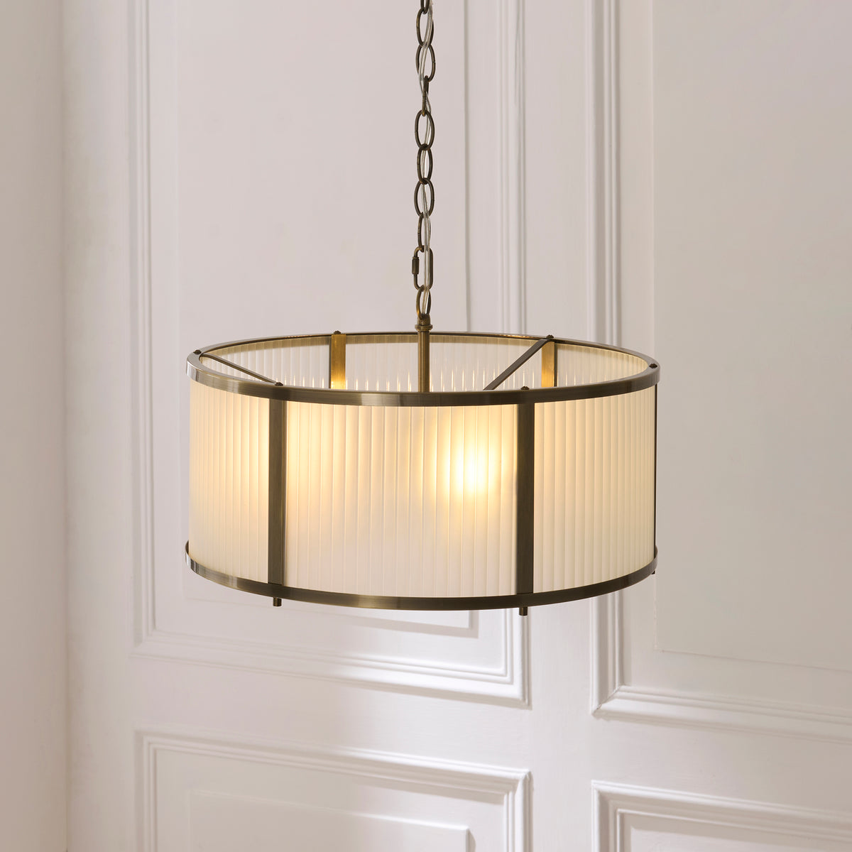 Angled view of the Ridgeton pendant's ribbed glass drum shade and brass framework