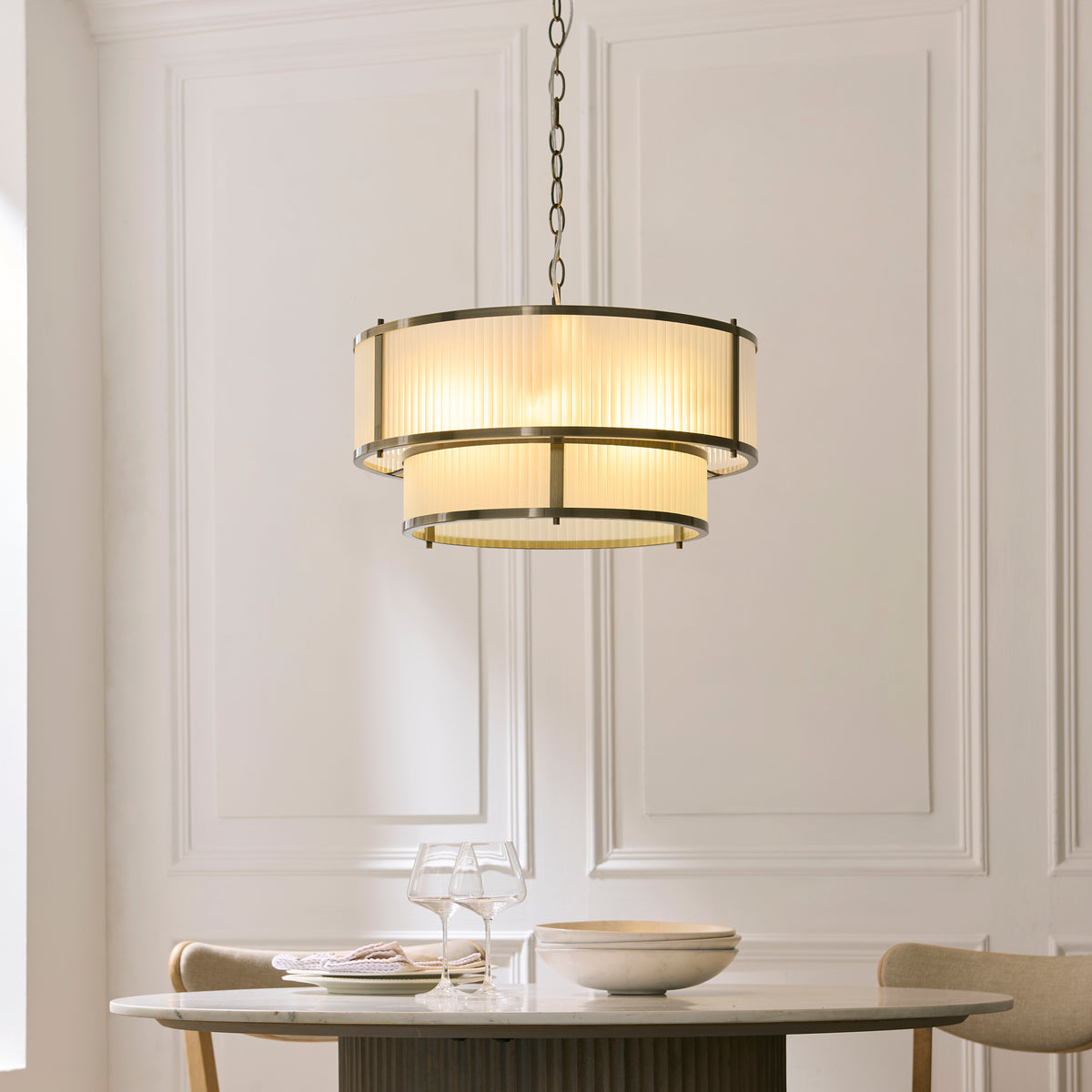 Ridgeton tiered pendant lit above a round dining table with glassware in a panelled dining room