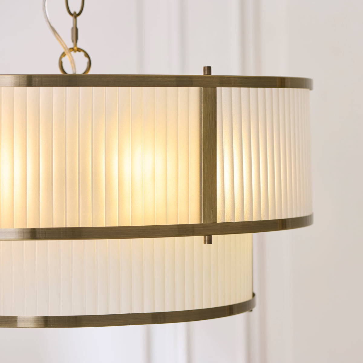 Close-up of the Ridgeton pendant's two ribbed cream shades and antique brass banding