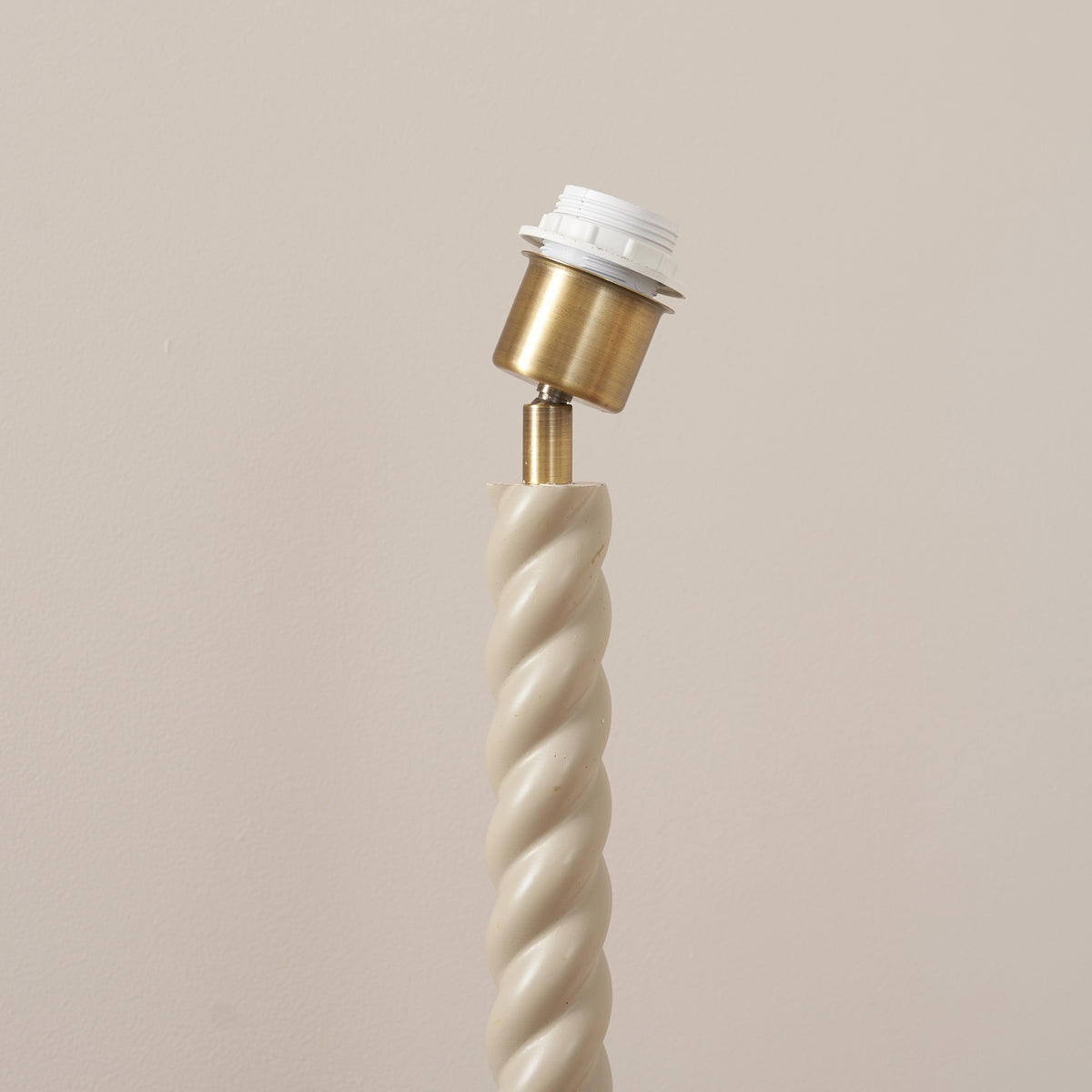 Close view of the Twist floor lamp's antique brass lamp holder and ribbed twisted column