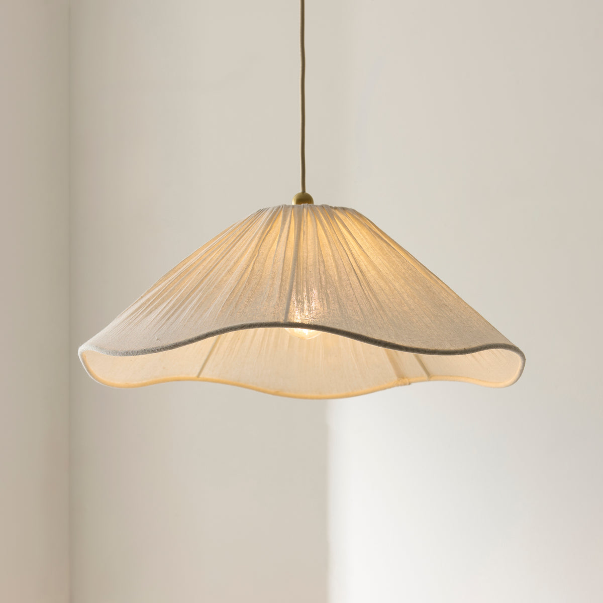 Isabella vintage white pendant glowing in a corner, its scalloped pleated shade catching light