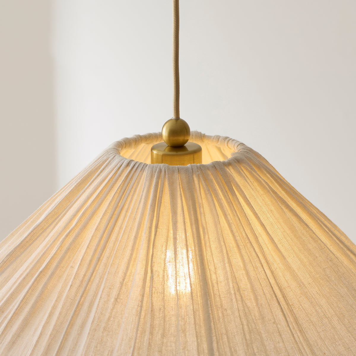 Detail of the Isabella pendant's brass fitting where the pleated shade gathers at the top