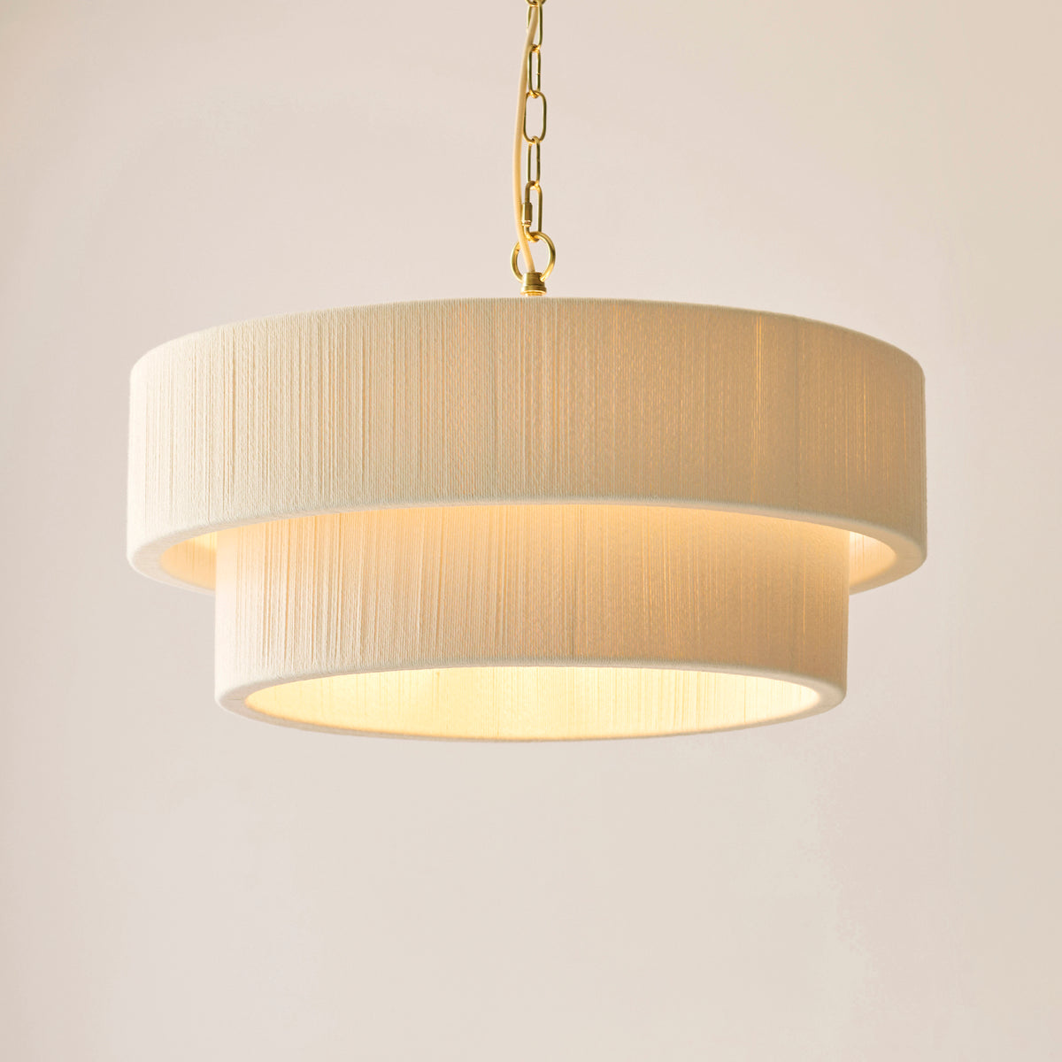 Noah tiered cream drum shades glowing on a brushed brass chain