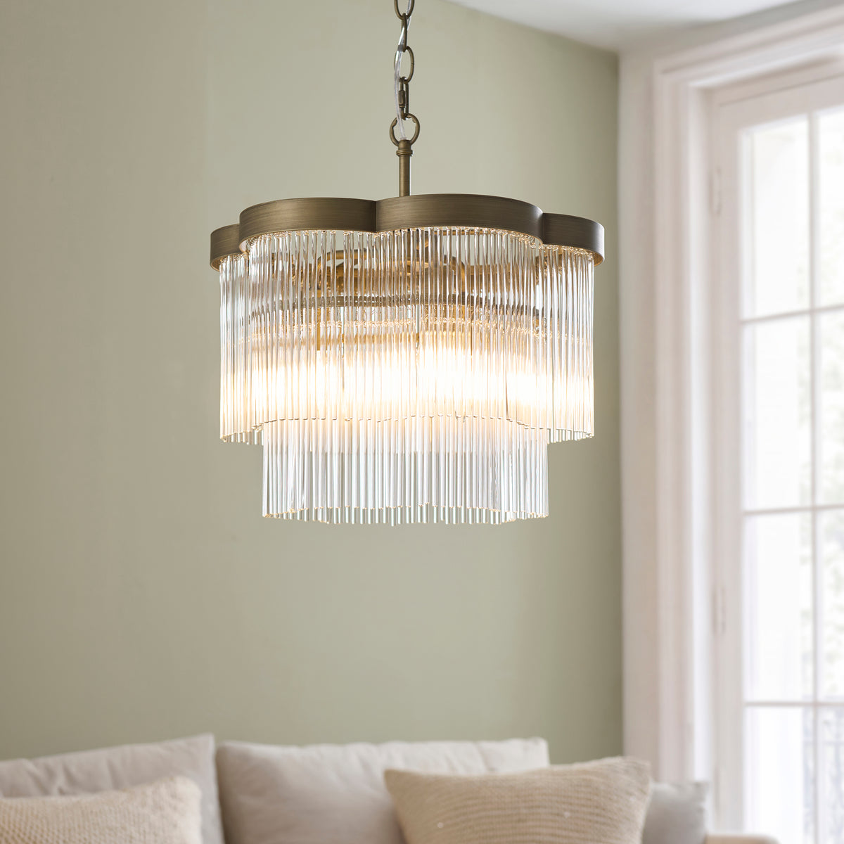 Illuminated Lucille chandelier's two tiers of clear glass rods and antique brass frame