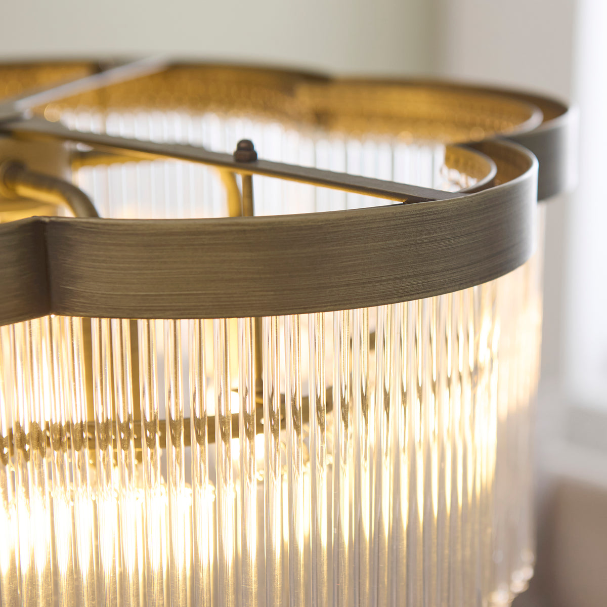 Close-up of the Lucille chandelier's antique brass band above dense clear glass rods