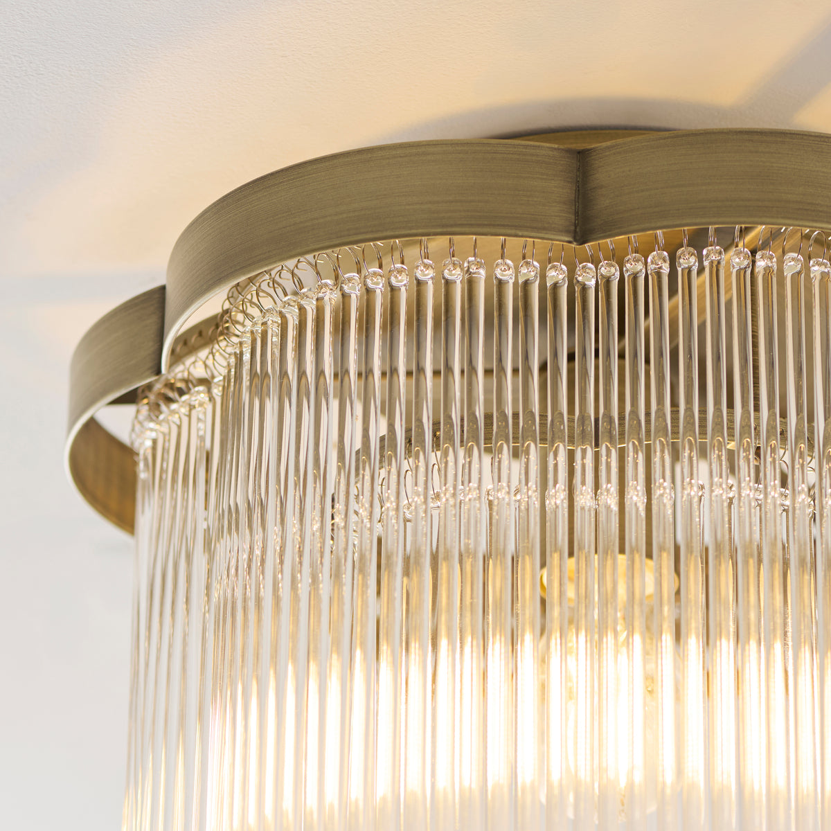 Close-up of the Lucille light's scalloped antique brass rim and closely set clear glass rods
