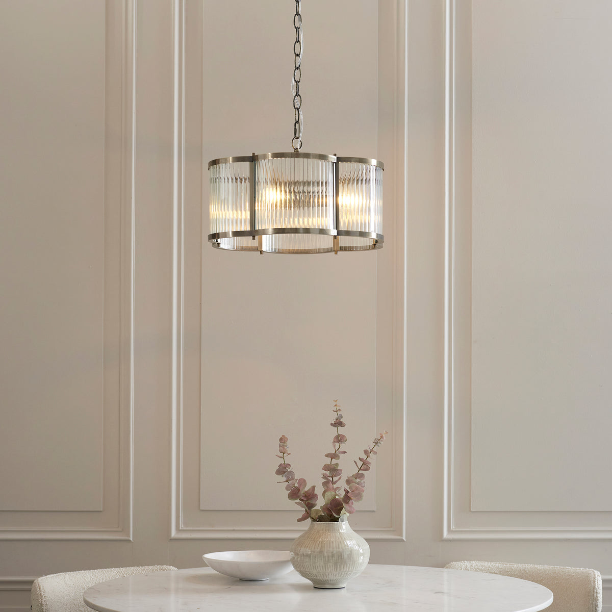 Ridgeton Scallop pendant lit above a round marble dining table with a vase of dried flowers
