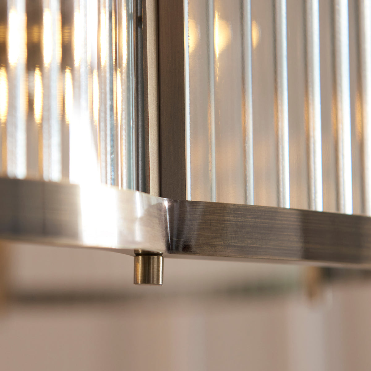 Detail of the brushed antique brass frame joint and ribbed glass panel on the Ridgeton chandelier