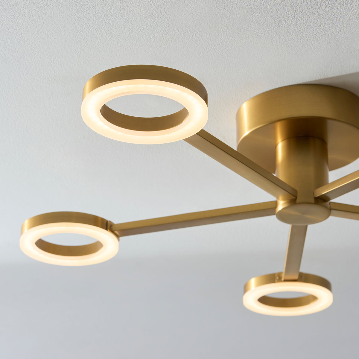 Close-up of three glowing LED rings on the Scout light's brushed warm brass arms