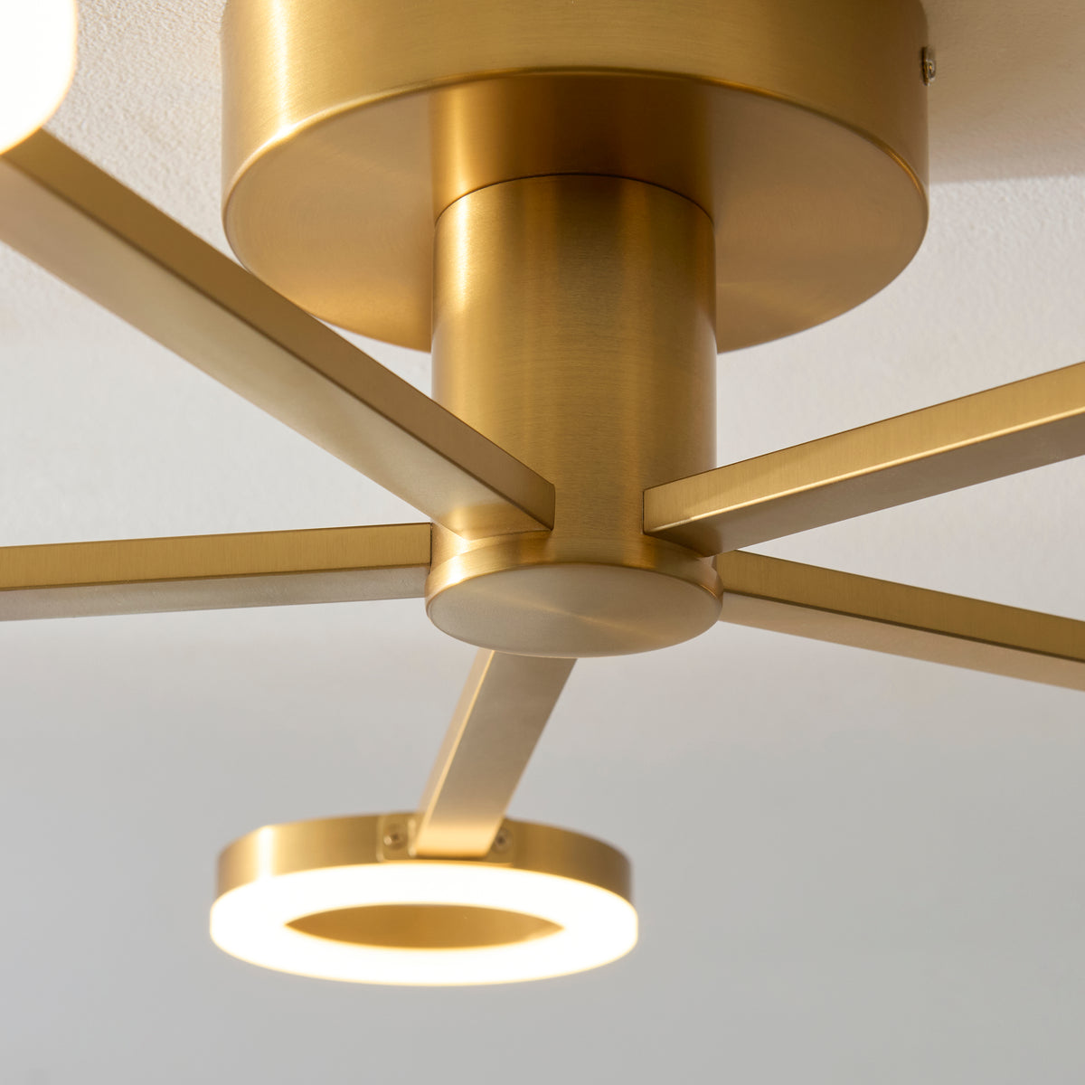 Close-up of the Scout light's warm brass central canopy and radiating arms with a lit ring