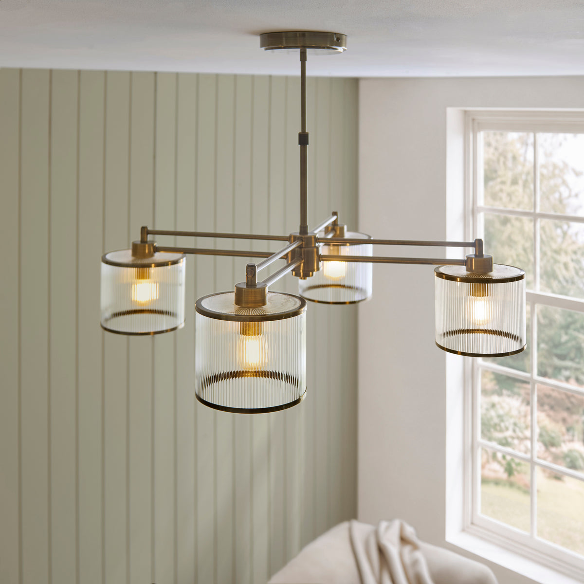 Ridgeton chandelier glowing above a cream sofa against sage green panelling