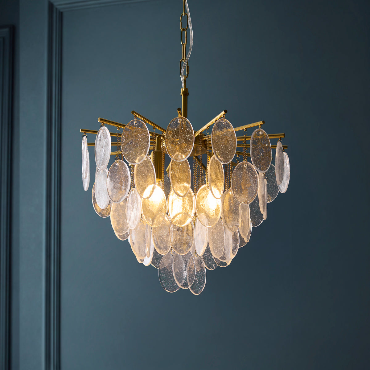 Loretta pendant glowing against dark blue walls, showing layered oval glass plates