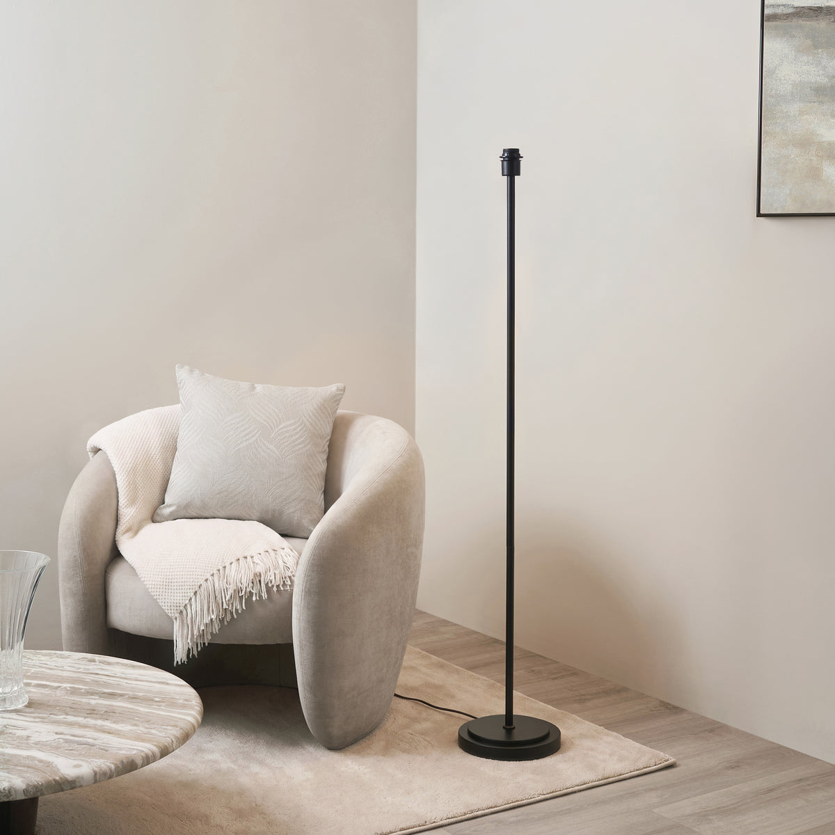 Arlo matt black floor lamp base beside a cream boucle armchair in a neutral living room