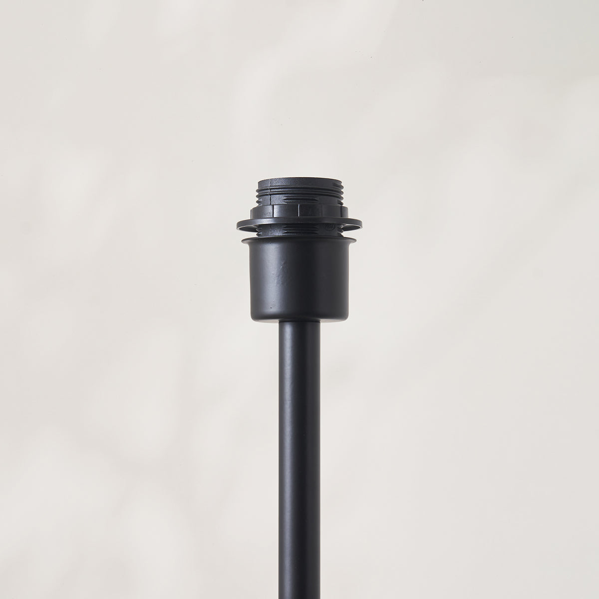 Detail of the Arlo floor lamp base's matt black threaded E27 lampholder and stem