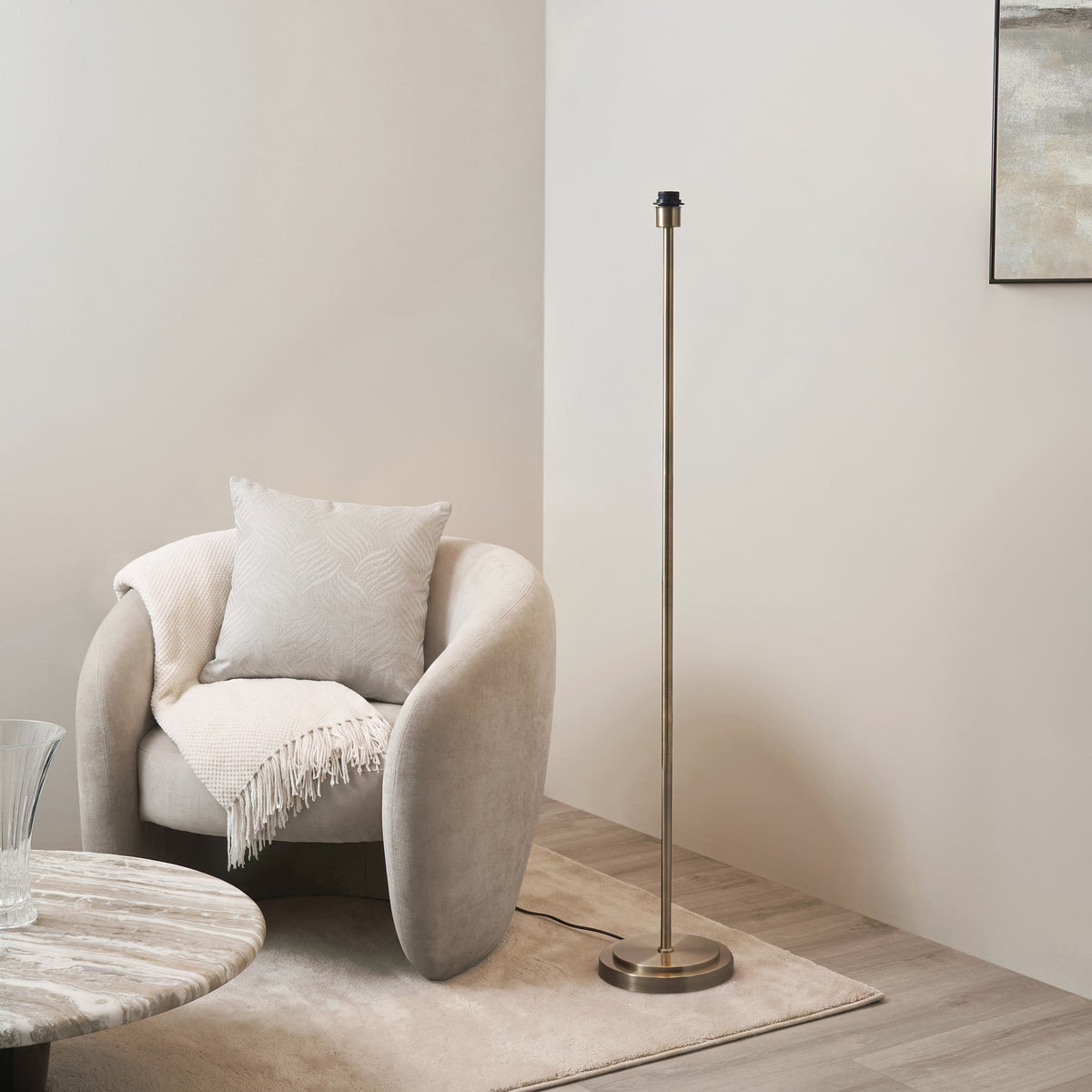 Arlo antique brass floor lamp base next to a cream boucle armchair and marble side table