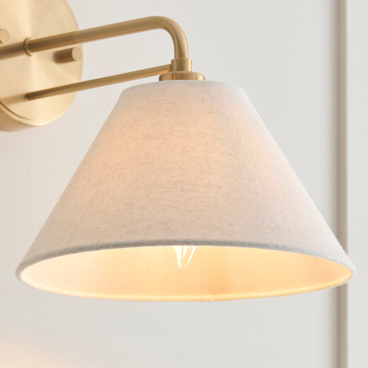 Close-up of the Wallbridge light's textured cream linen coolie shade with lit candle bulb inside