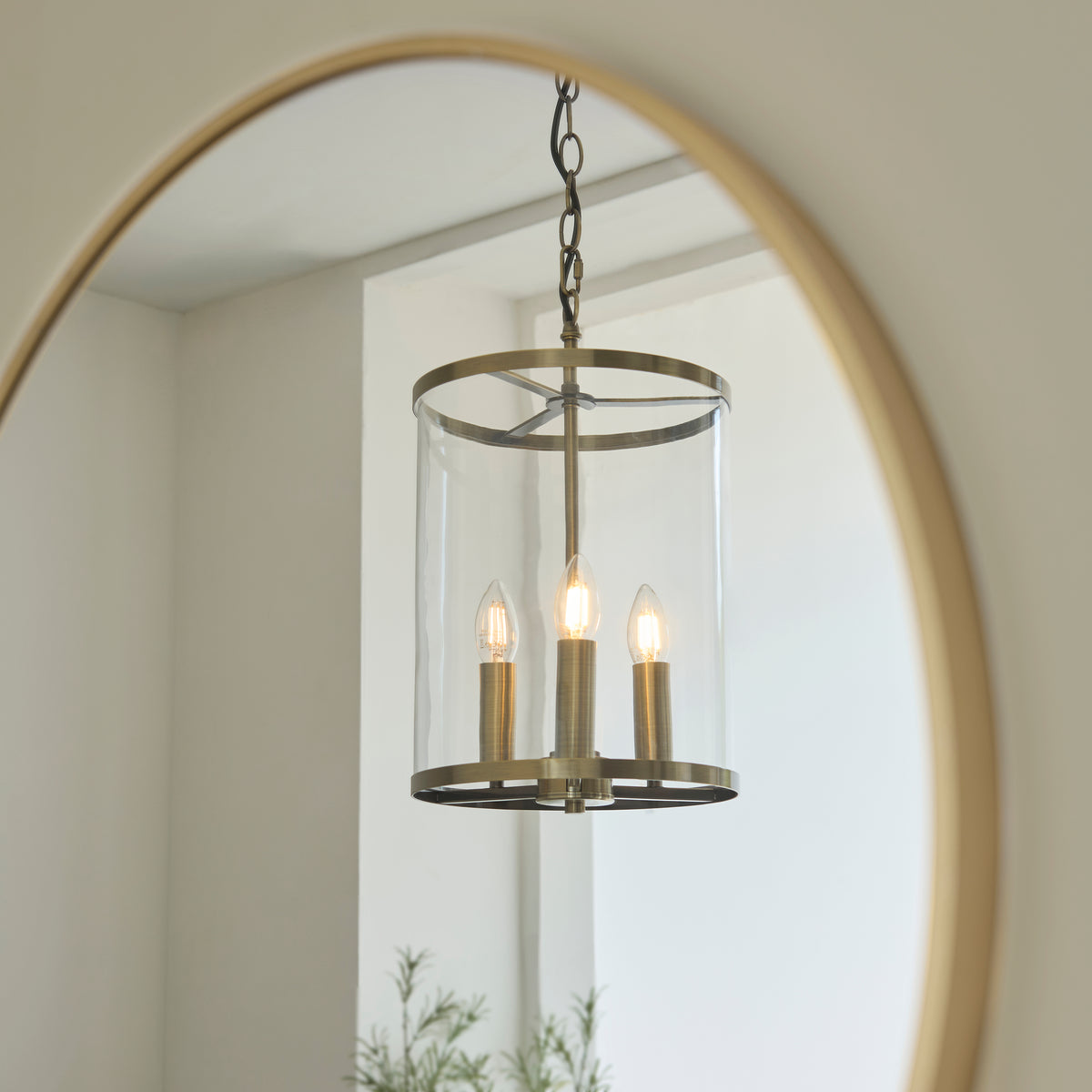 Hebden lantern pendant reflected in a round brass-framed hallway mirror