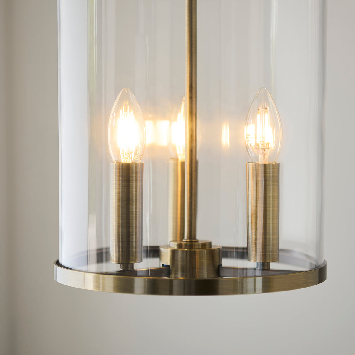 Close-up of the Hebden pendant's three lit candle bulbs inside its clear glass cylinder