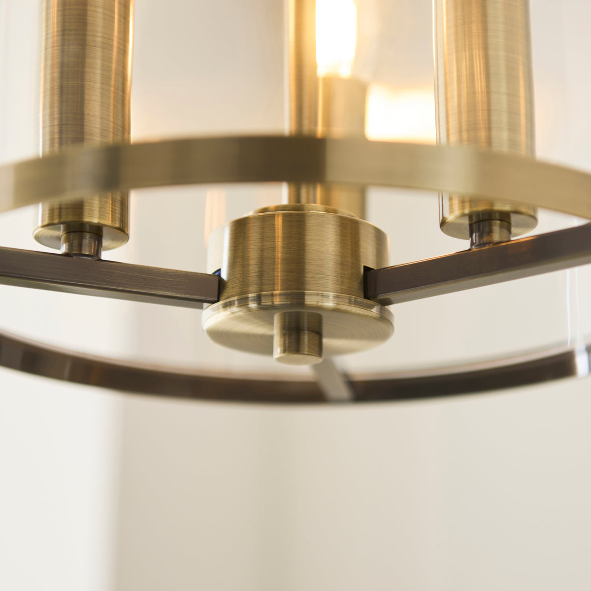 Detail of the Hebden pendant's antique brass ring frame and lamp holders behind clear glass