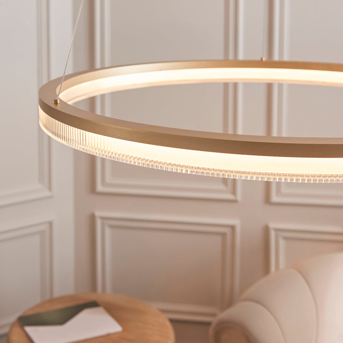 Close-up of the Lansina ring pendant's brushed gold frame and ribbed light diffuser