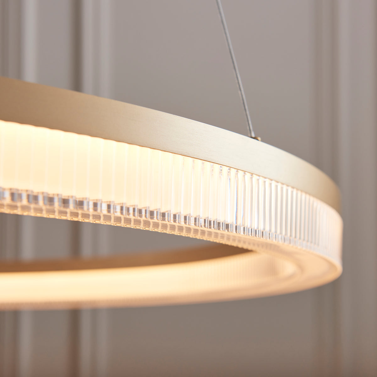 Detail of the Lansina pendant's ribbed acrylic diffuser edge and brushed gold rim