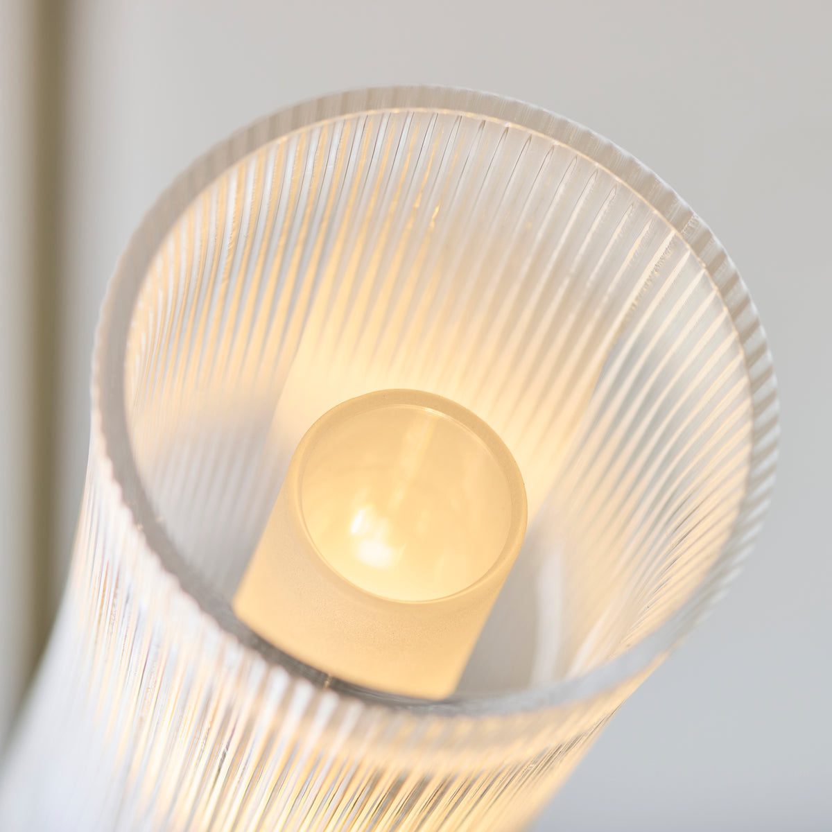 Close-up inside an Avelyn ribbed glass shade showing the lit bulb