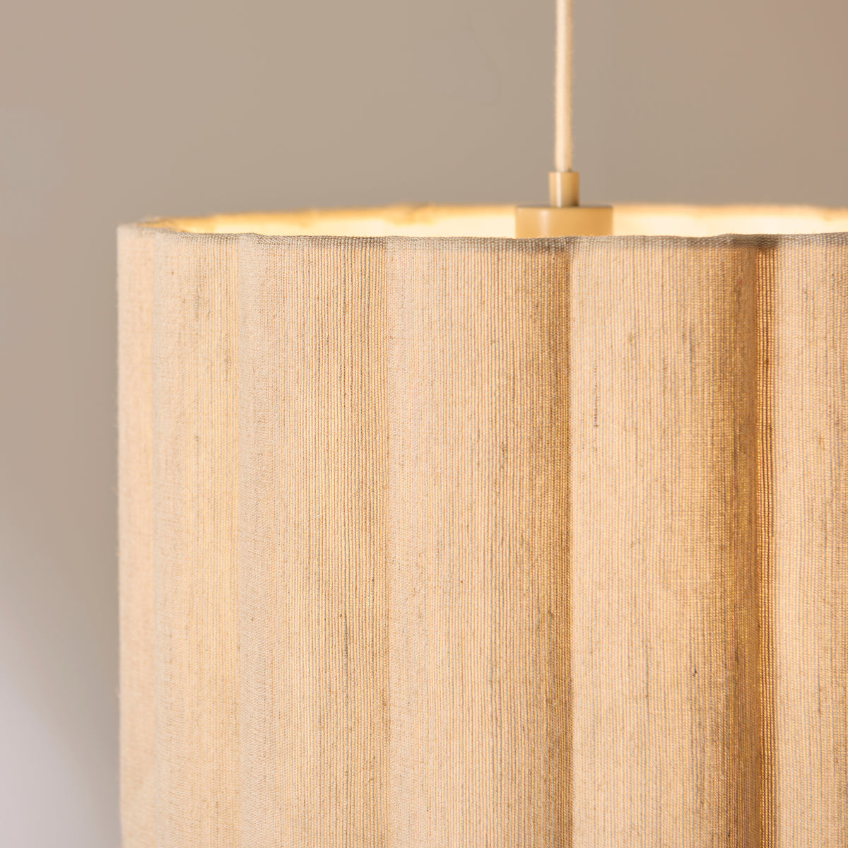 Close-up of the Olson pendant's scalloped fabric shade and brass lamp holder inside