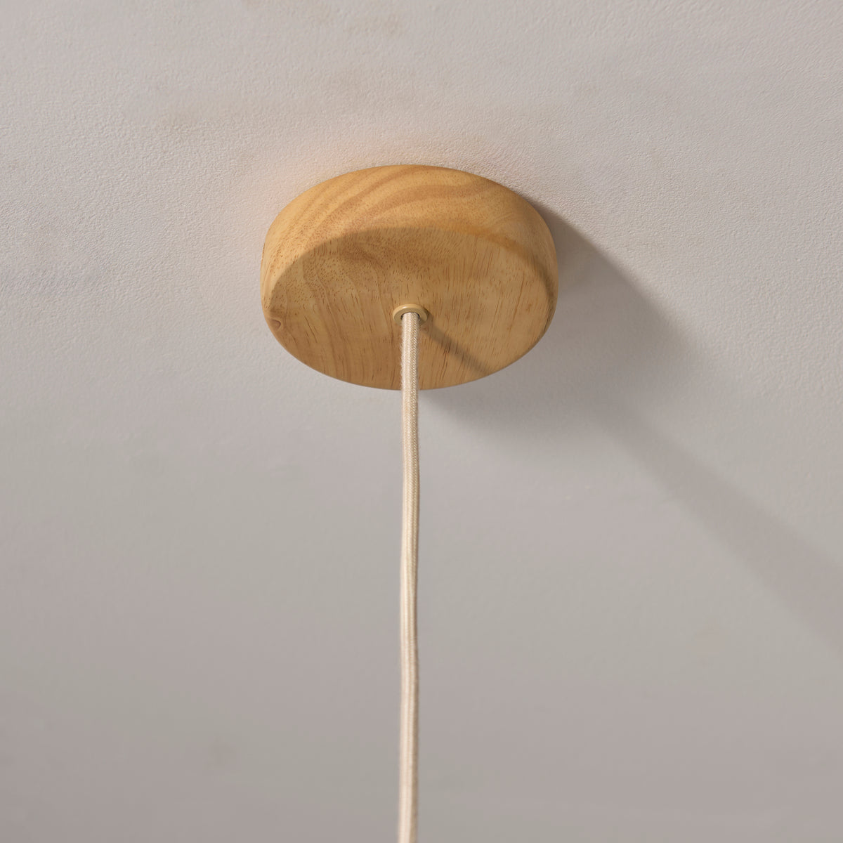 Oak ceiling rose and cream flex of the Olson pendant fixed to a pale ceiling