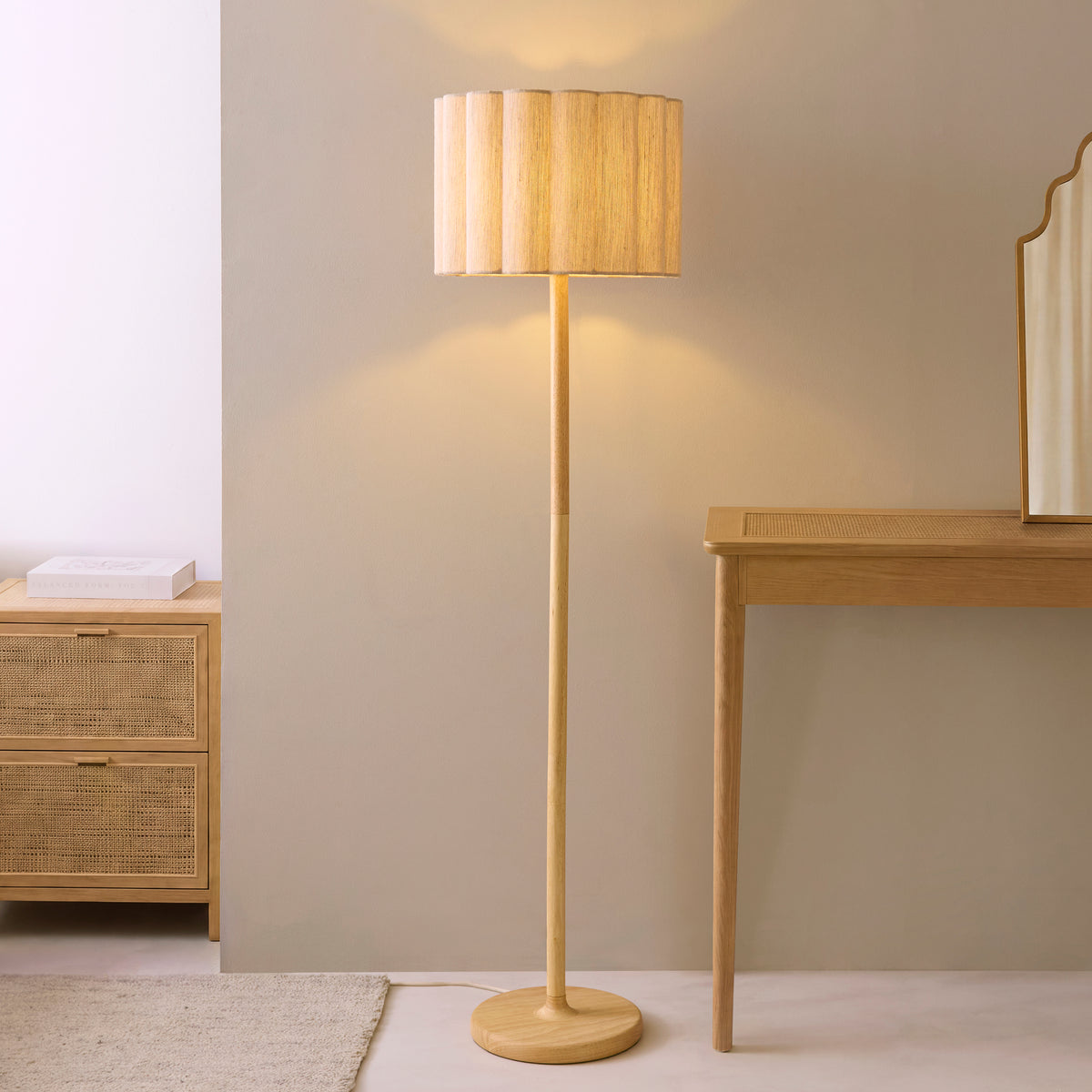 Olson wood floor lamp glowing softly next to an oak console table against a pale grey bedroom wall