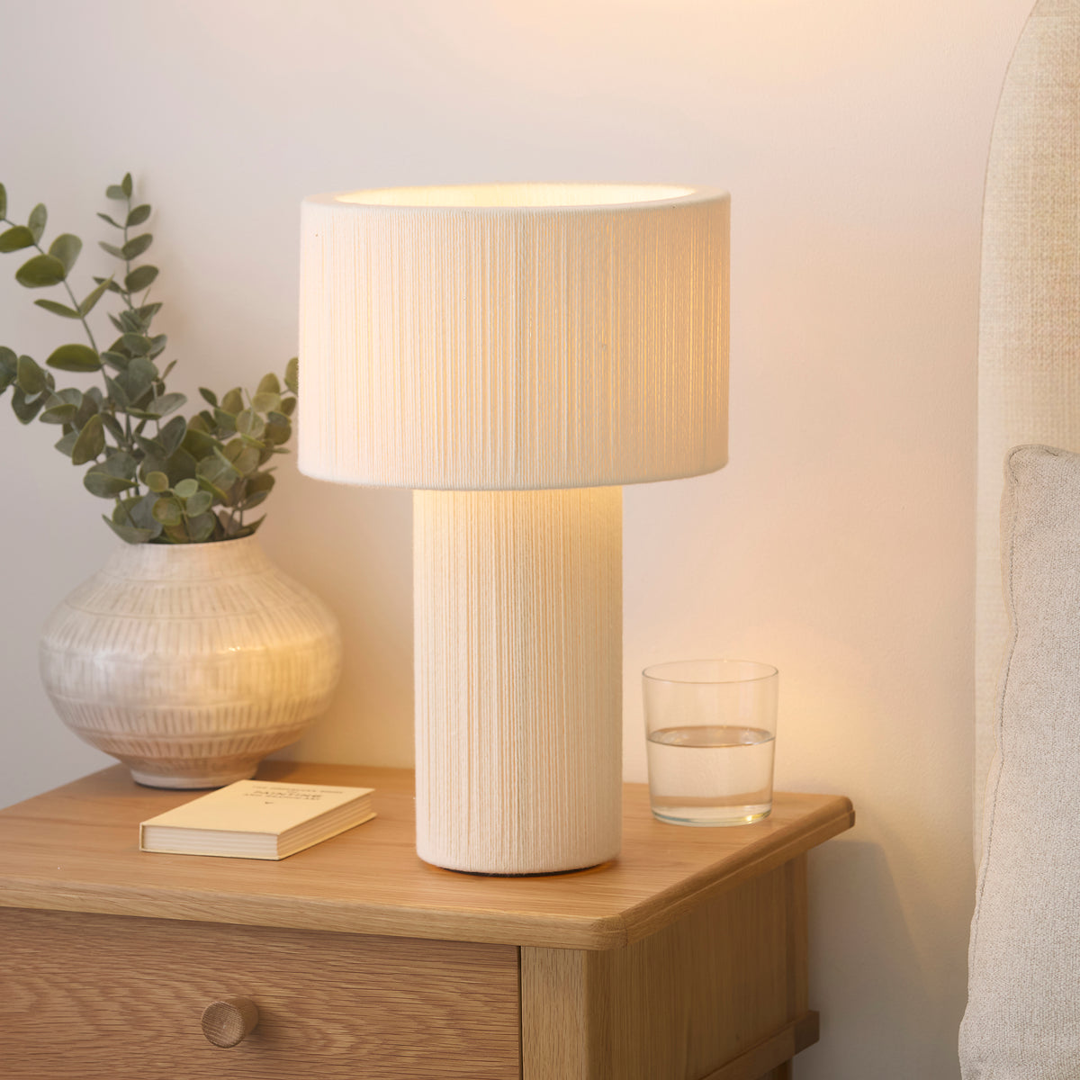 Noah cream cord-wrapped table lamp casting warm light on a bedside table in a calm bedroom