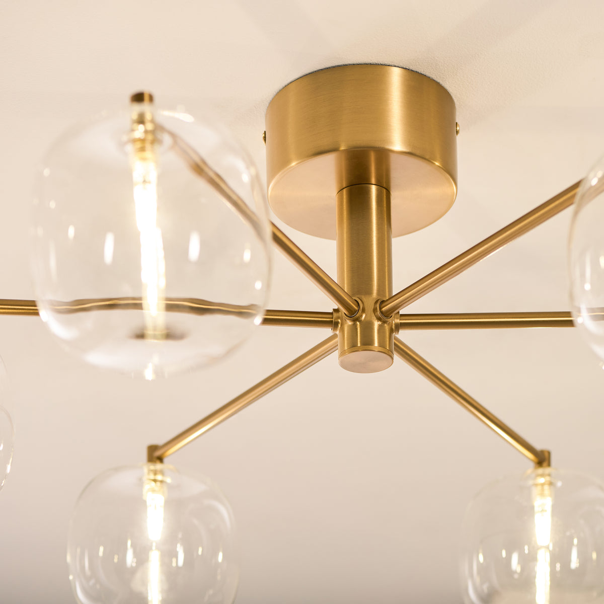 Close-up of the Oslo light's aged brass ceiling plate and arms holding clear glass globe shades