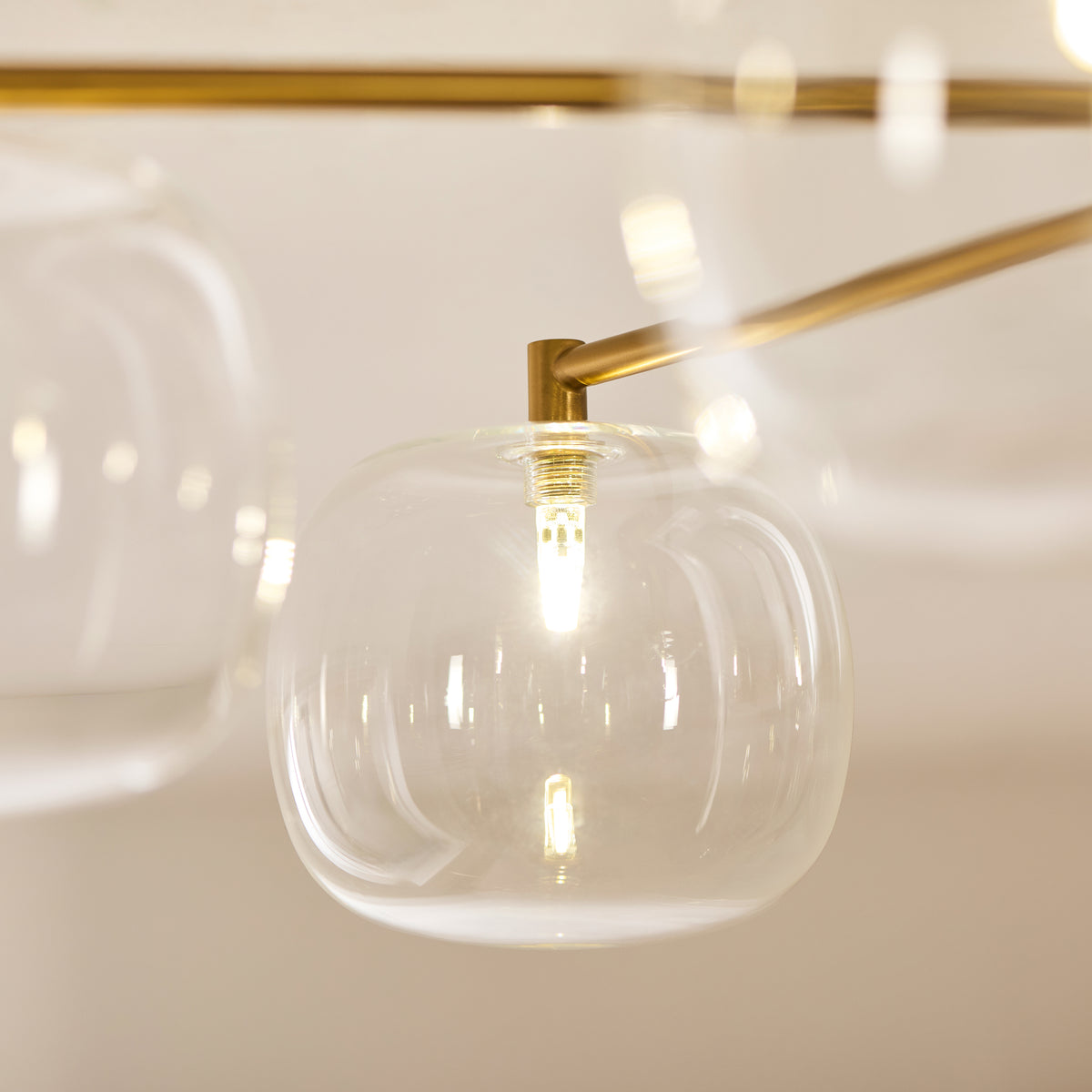 Detail of a single clear glass globe on the Oslo fitting with a lit filament bulb inside