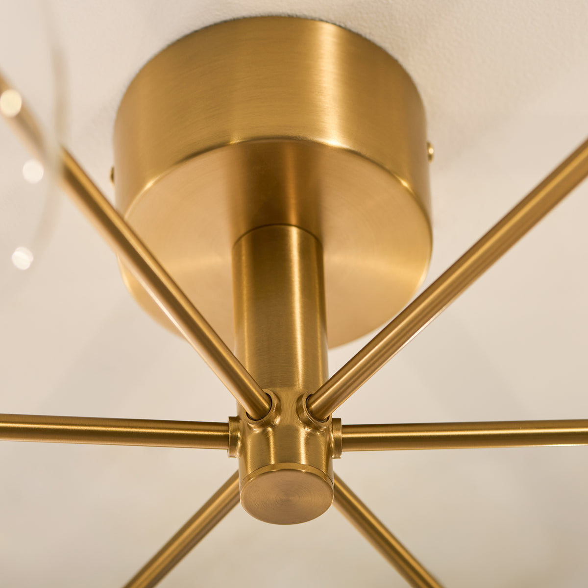 Aged brass ceiling plate and radiating arms of the Oslo semi flush light seen from beneath