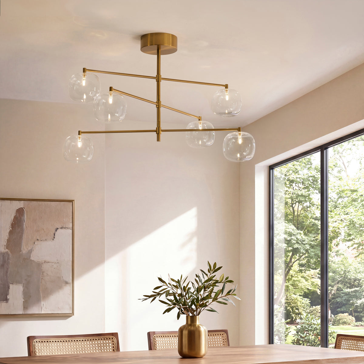Oslo brass multi-arm glass pendant lit above a cane dining table beside a large garden window