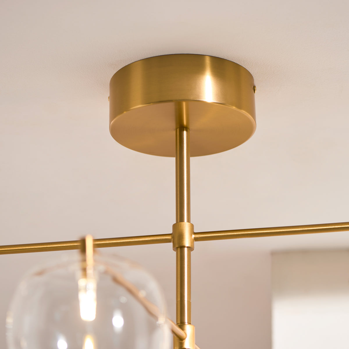 Brushed brass ceiling rose and drop rod of the Oslo adjustable-arm glass pendant